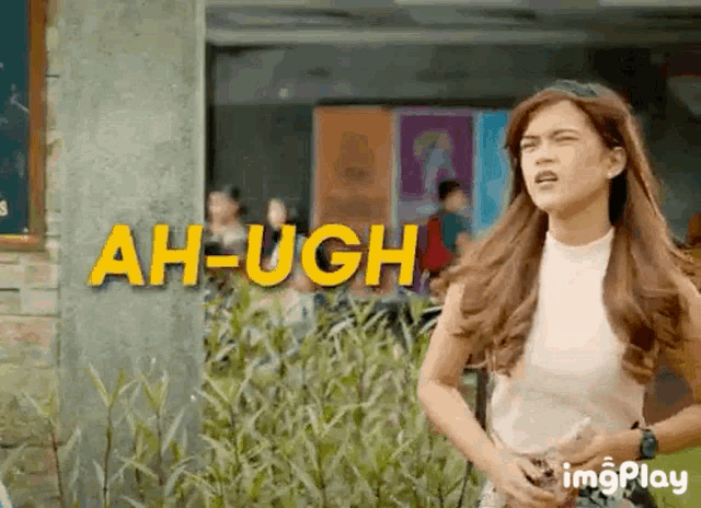 a woman is standing in front of a sign that says ah-ugh
