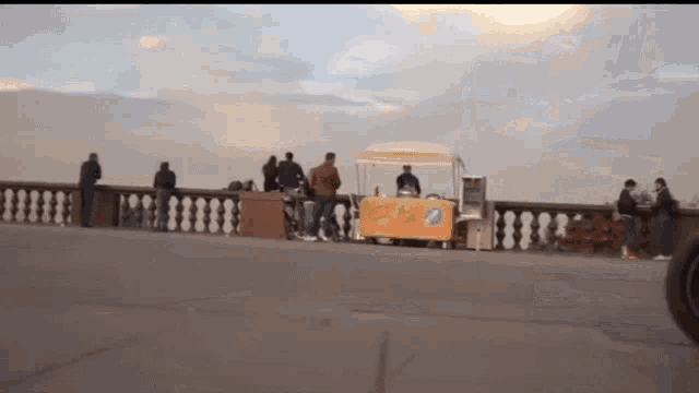 a blurred image of people standing around a food stand that says ' ice cream ' on it