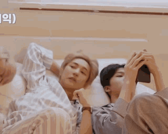 a man laying on a bed looking at his phone