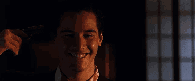 a man in a suit and tie is smiling while holding a gun