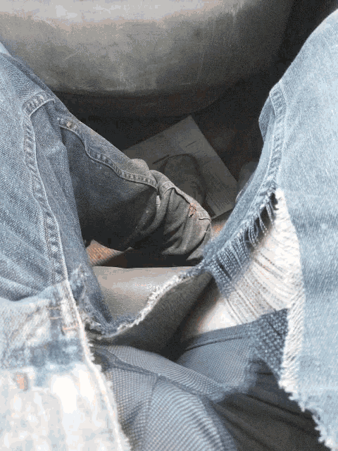 a person wearing a pair of ripped jeans sits on a tire