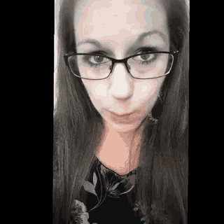 a woman wearing glasses and a black shirt is making a funny face .