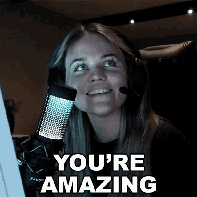 a woman holding a microphone with the words " you 're amazing " above her