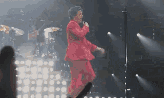 a man in a red suit is standing on a stage holding a microphone .