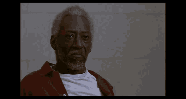 a man with gray hair and a beard wearing a red shirt and white shirt