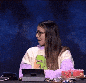 a woman wearing glasses is sitting at a table using a tablet computer .