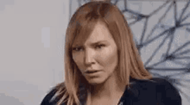 a woman with long red hair is making a funny face in a room .