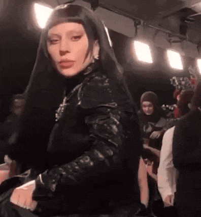 a woman wearing a black veil and a black jacket is standing in a crowd of people .