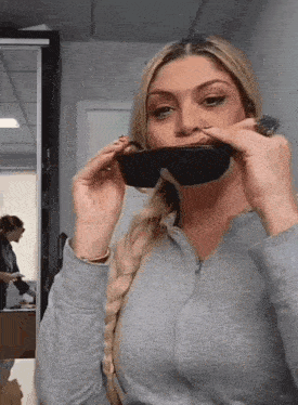 a woman is wearing sunglasses in front of a mirror in a room .