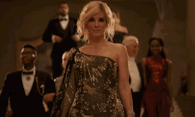 a woman in a one shoulder dress is standing in front of a group of people