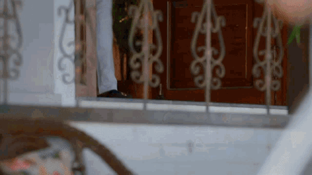 a person standing in front of a door with a wrought iron railing ..