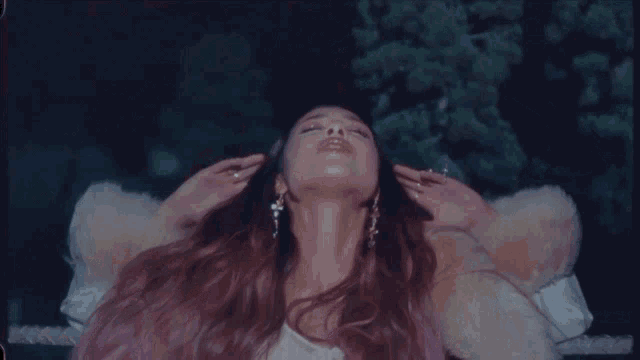 a woman in a fur coat is laying down with her hands on her head
