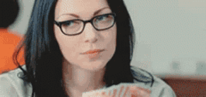 a woman wearing glasses is holding a deck of cards in her hand .