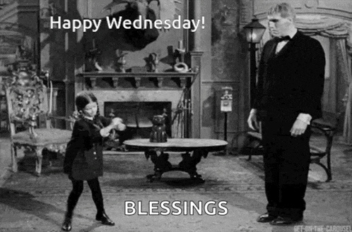 a black and white photo of a little girl dancing next to a man in a tuxedo in a living room .