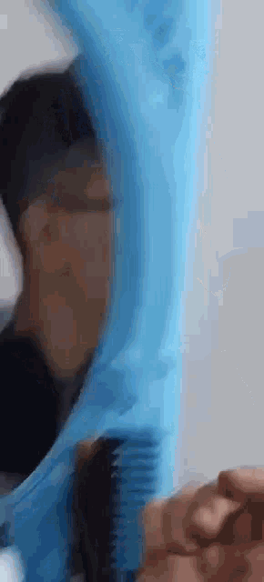 a person wearing a blue glove is holding a comb .