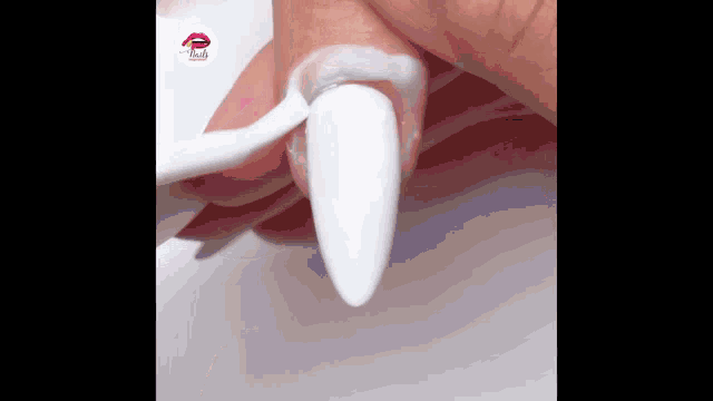 a woman is applying white nail polish to her nails