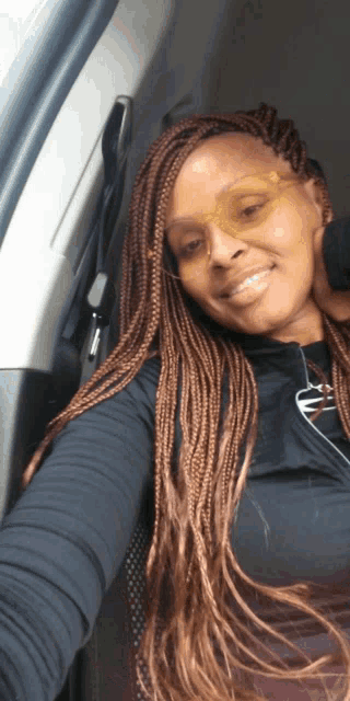 a woman wearing braids and sunglasses is smiling for the camera