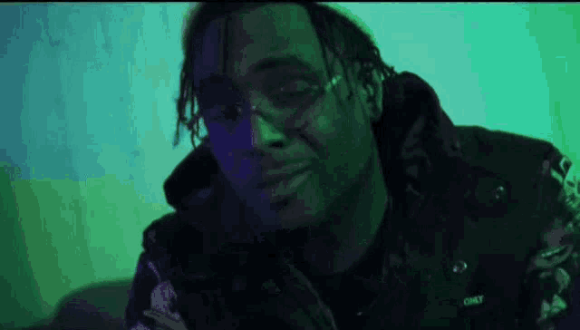 a man wearing glasses and a black jacket is looking at the camera in a dark room .