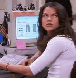 a woman is sitting at a desk in front of a computer with a picture of pants on it