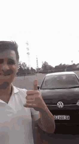 a man gives a thumbs up in front of a volkswagen