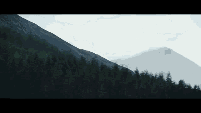 a mountain with trees on the side of it and a cloudy sky