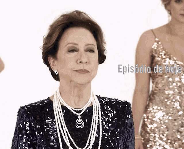 a woman in a sequined dress stands next to a woman in a gold dress and the words episodio de hoje are visible