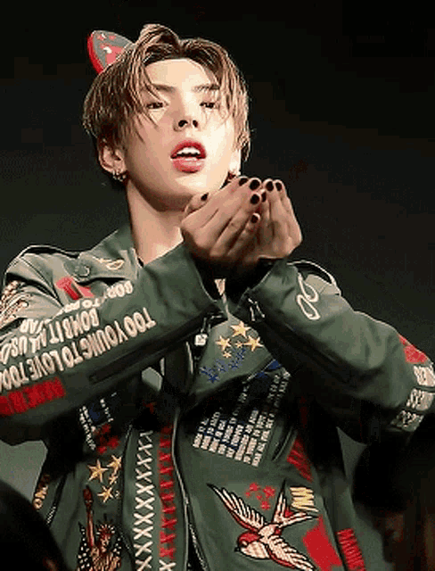 a young man wearing a green jacket that says " too young to love too "
