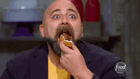 a bald man with a beard is eating a piece of food .