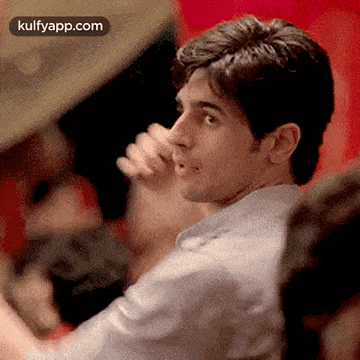 a man is covering his nose with his hand while sitting in a crowd of people .