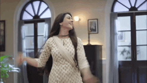 a woman in a white dress is dancing in a room with a lot of windows .