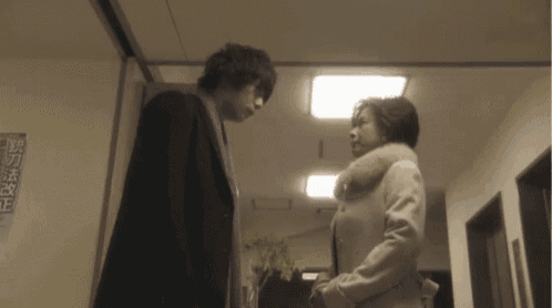 a man and a woman are standing next to each other in a hallway with chinese characters on the wall
