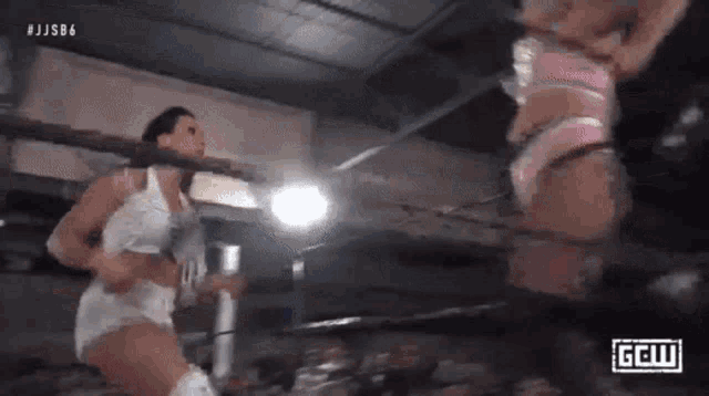 two women are wrestling in a ring and one is kneeling down .