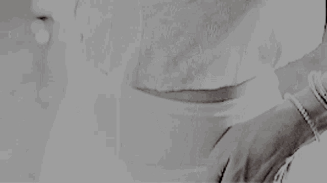 a black and white photo of a person holding a knife on their ankle .