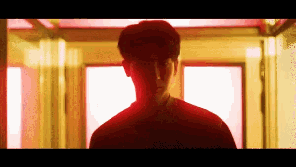 a man in a red shirt is standing in a hallway in front of a red light .