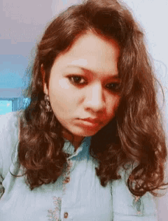 a woman in a blue shirt looks at the camera
