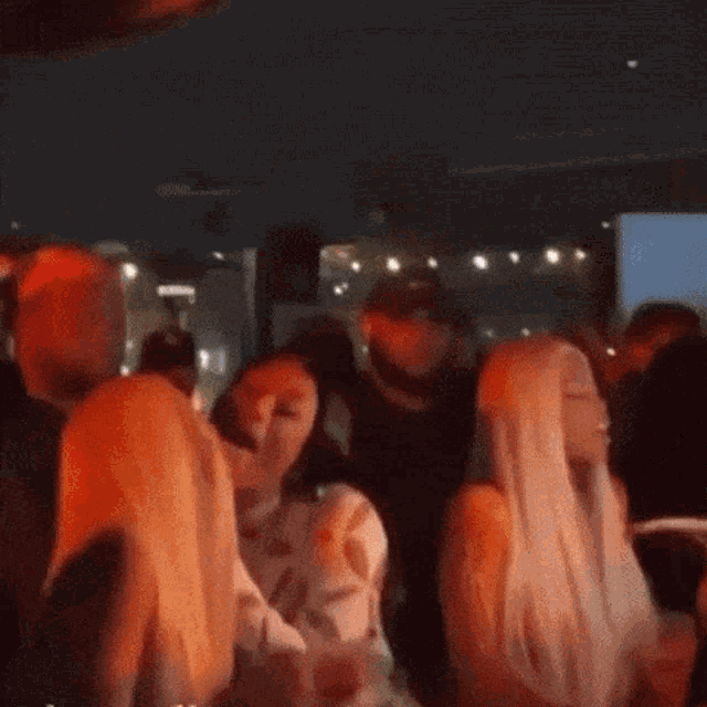 a group of people are dancing in a dark room at a party .