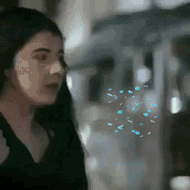 a woman in a black shirt is blowing blue bubbles in the air