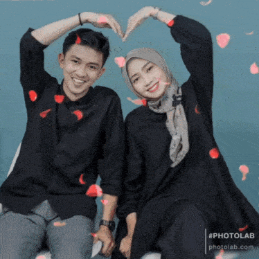 a man and a woman are making a heart with their hands