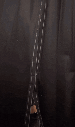 a woman is sitting in a chair behind a curtain