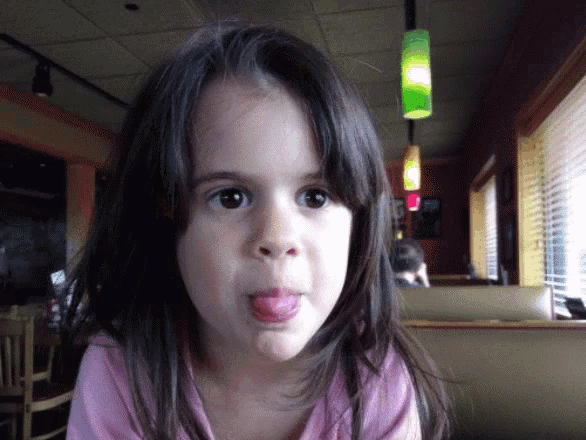 a young girl sticking her tongue out in a restaurant