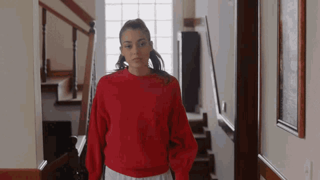 a woman in a red sweater is walking down stairs