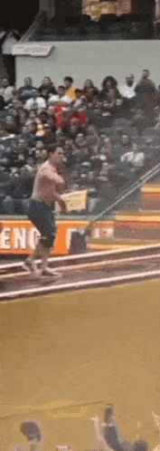 a shirtless man is running on a track in front of a crowd with a sign that says eng on it