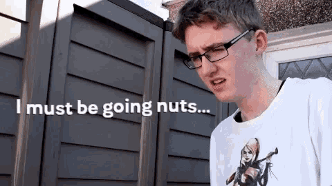 a young man wearing glasses is standing in front of a fence and says i must be going nuts