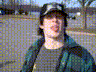 a man wearing a hat with the letter k on it sticks his tongue out