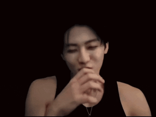 a woman covering her mouth with her hand in a dark room