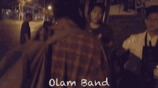 a group of people walking down a street with the word olan band on the bottom right