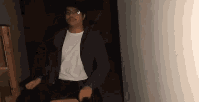 a man in a suit and glasses is sitting in a dark room .