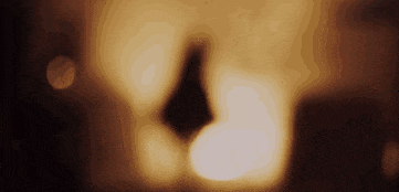 a close up of a candle in a dark room with a blurred background .