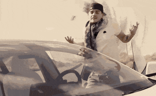 a man in a louis vuitton scarf is standing in front of a car