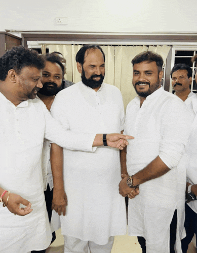 a group of men in white shirts are shaking hands and smiling